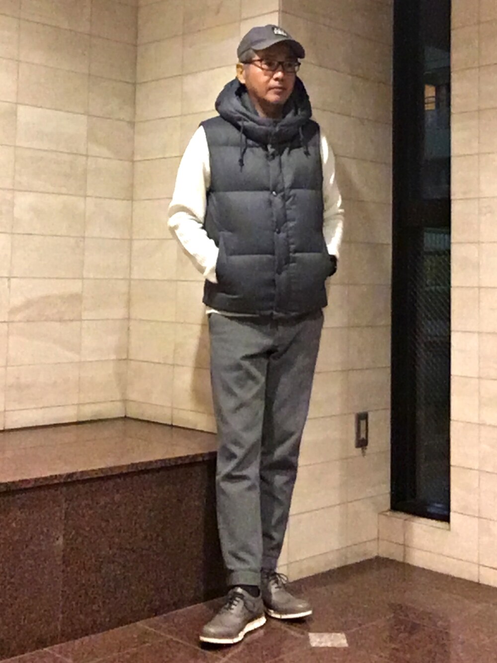 グレー系のダウンベスト、ホワイト系のニット/セーター、グレー系のその他パンツを着用したメンズの春コーディネートの1枚目の写真