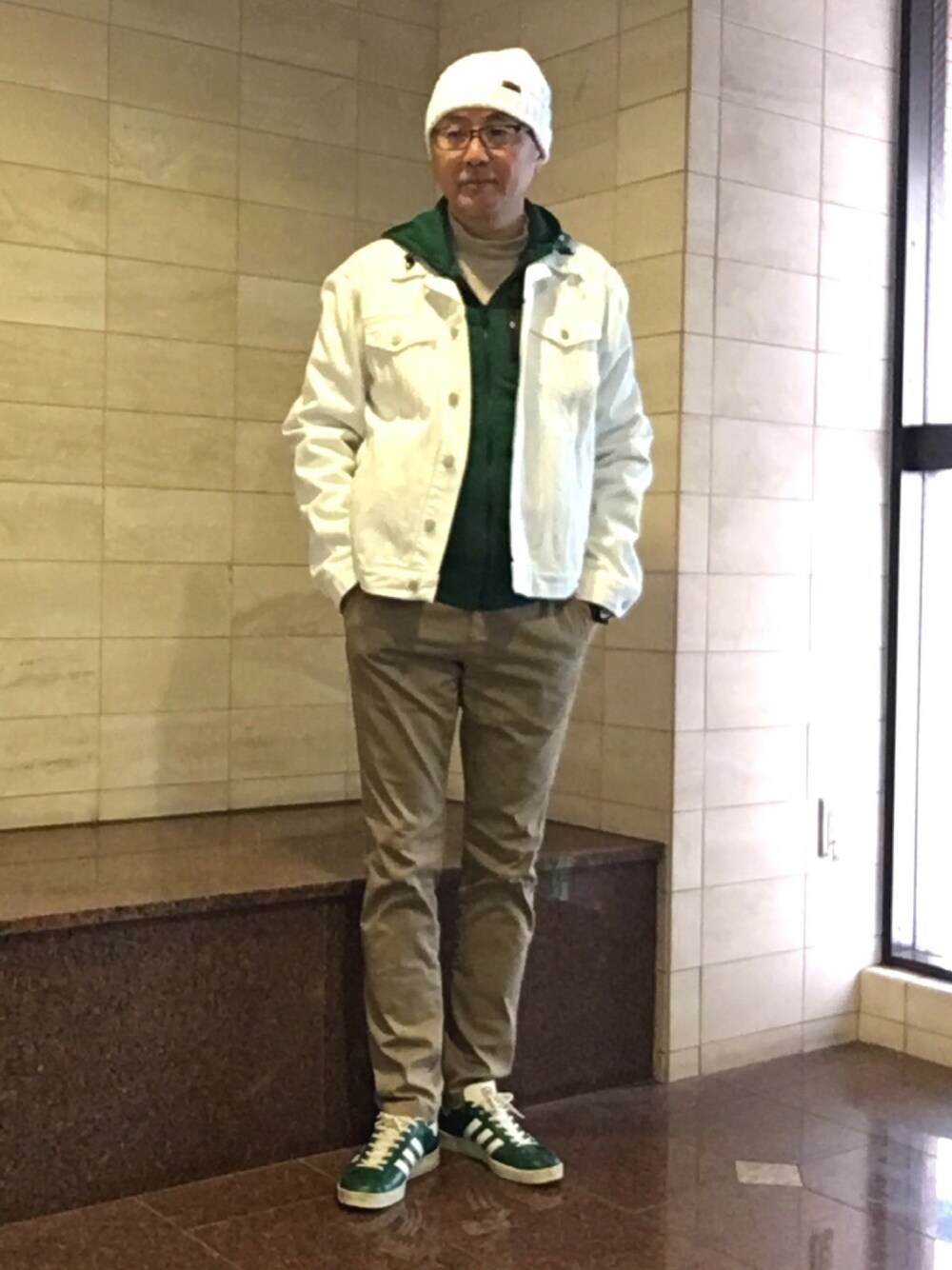 ホワイト系のデニムジャケット、ベージュ系のチノパンツ、グリーン系のスニーカーを着用したメンズの春コーディネートの1枚目の写真