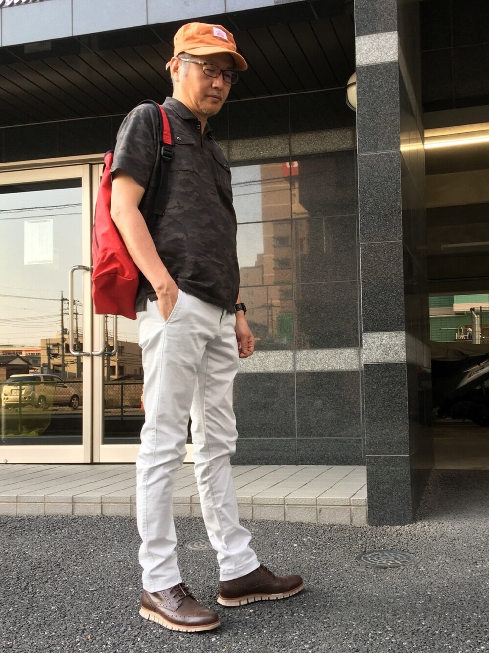 ブラウン系のポロシャツ、グレー系のチノパンツ、ブラウン系のブーツを着用したメンズの春コーディネートの1枚目の写真