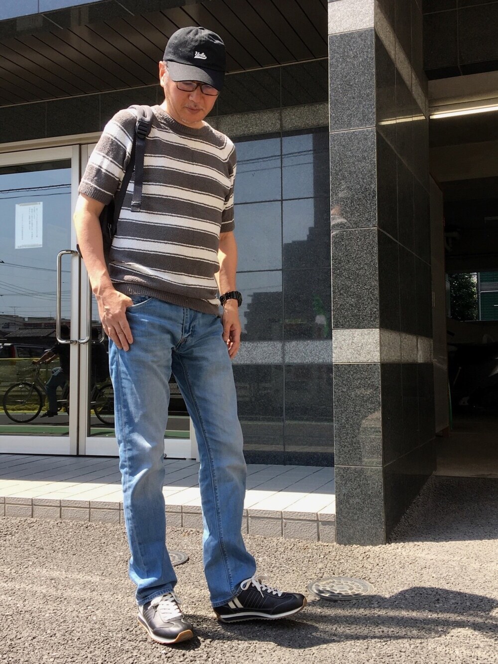 グレー系のTシャツ/カットソー、ブルー系のデニムパンツ、ブラック系のスニーカーを着用したメンズの春コーディネートの1枚目の写真