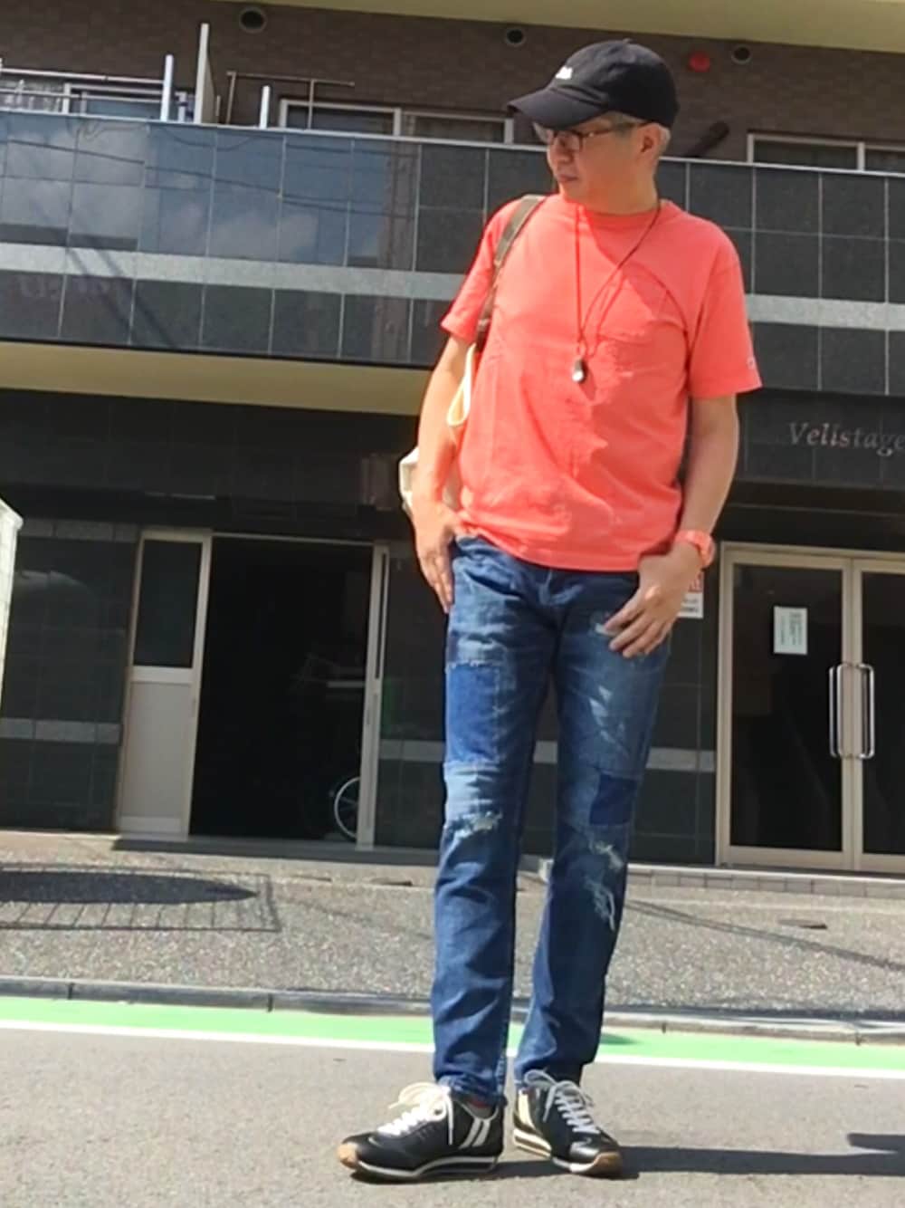 ブルー系のデニムパンツ、ピンク系のTシャツ/カットソー、ブラック系のスニーカーを着用したメンズの夏コーディネートの1枚目の写真