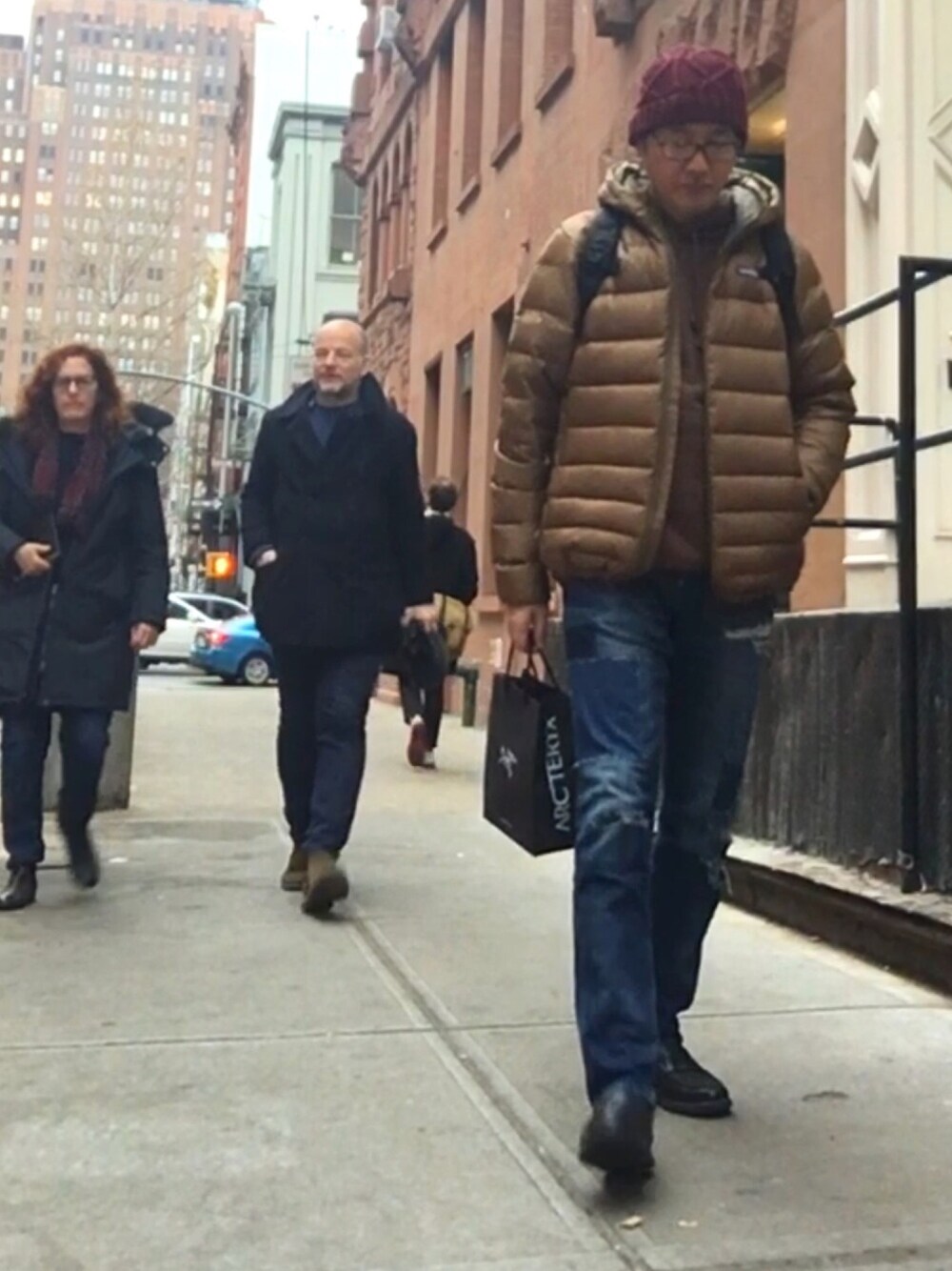 ブラウン系のダウンジャケット/コート、ブラウン系のパーカー、ブルー系のデニムパンツを着用したメンズの冬コーディネートの1枚目の写真