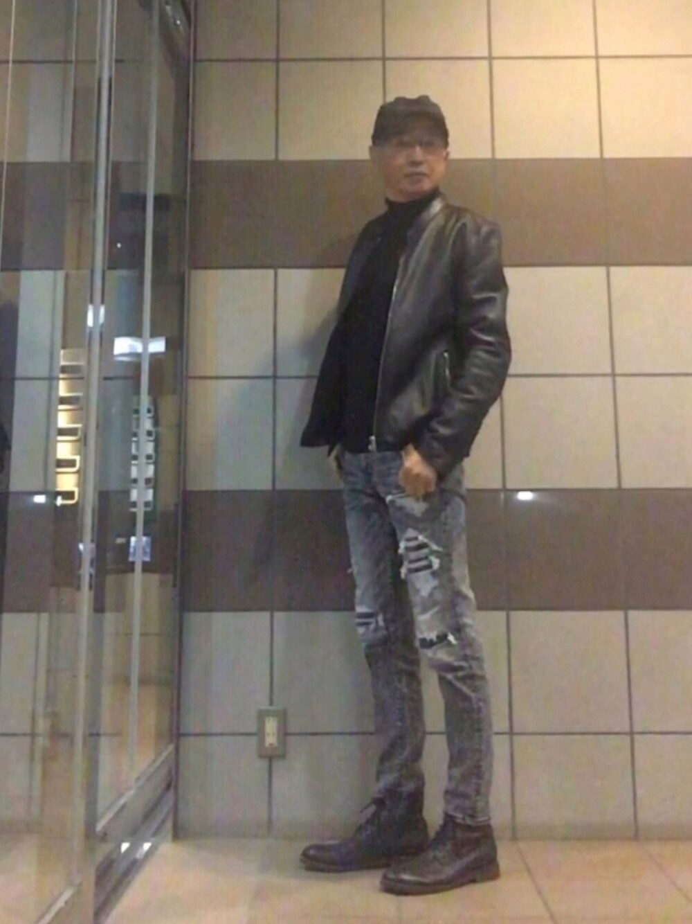 ブラック系のライダースジャケット、ブラック系のデニムパンツ、ブラック系のブーツを着用したメンズの冬コーディネートの1枚目の写真