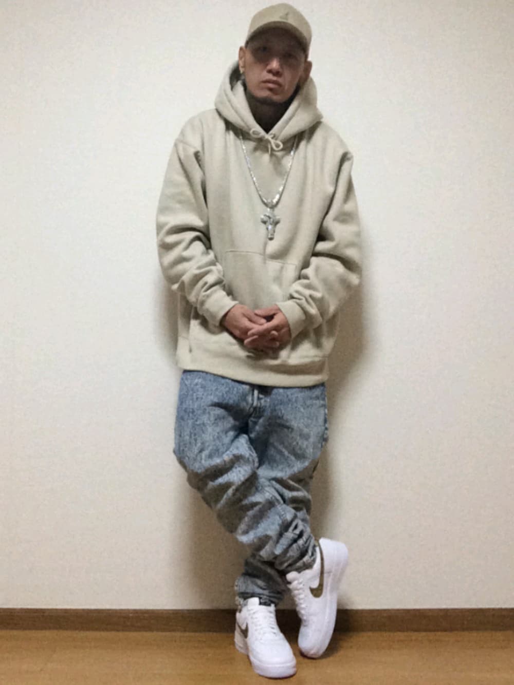 ブルー系のデニムパンツ、ホワイト系のスニーカー、ベージュ系のパーカーを着用したメンズの秋コーディネートの1枚目の写真