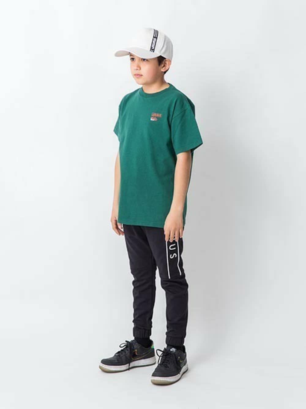 グリーン系のTシャツ/カットソー、ブラック系のその他パンツ、ホワイト系のキャップを着用したキッズの春コーディネートの1枚目の写真