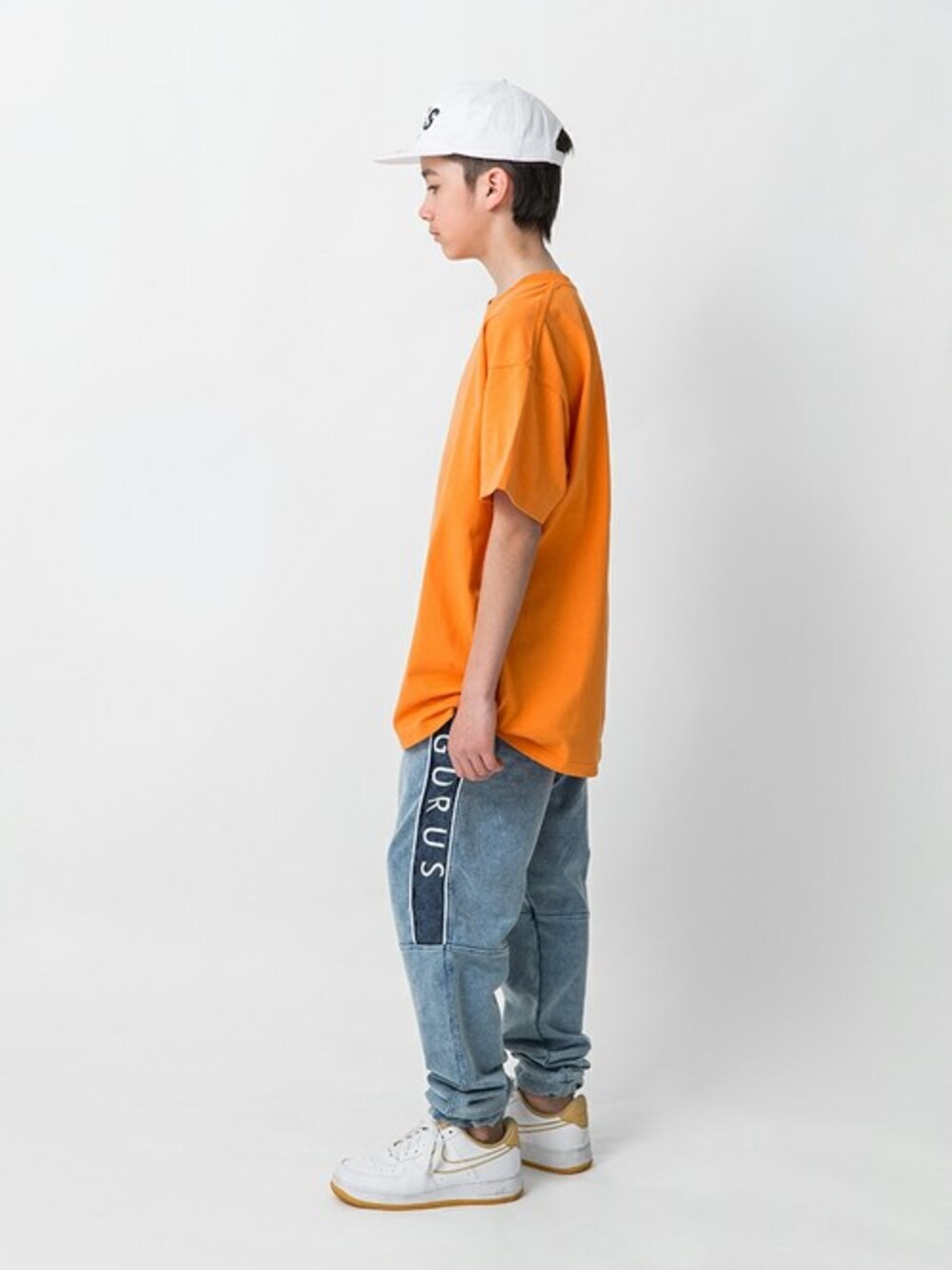 オレンジ系のTシャツ/カットソー、ブルー系のその他パンツ、ホワイト系のキャップを着用したキッズの春コーディネートの1枚目の写真