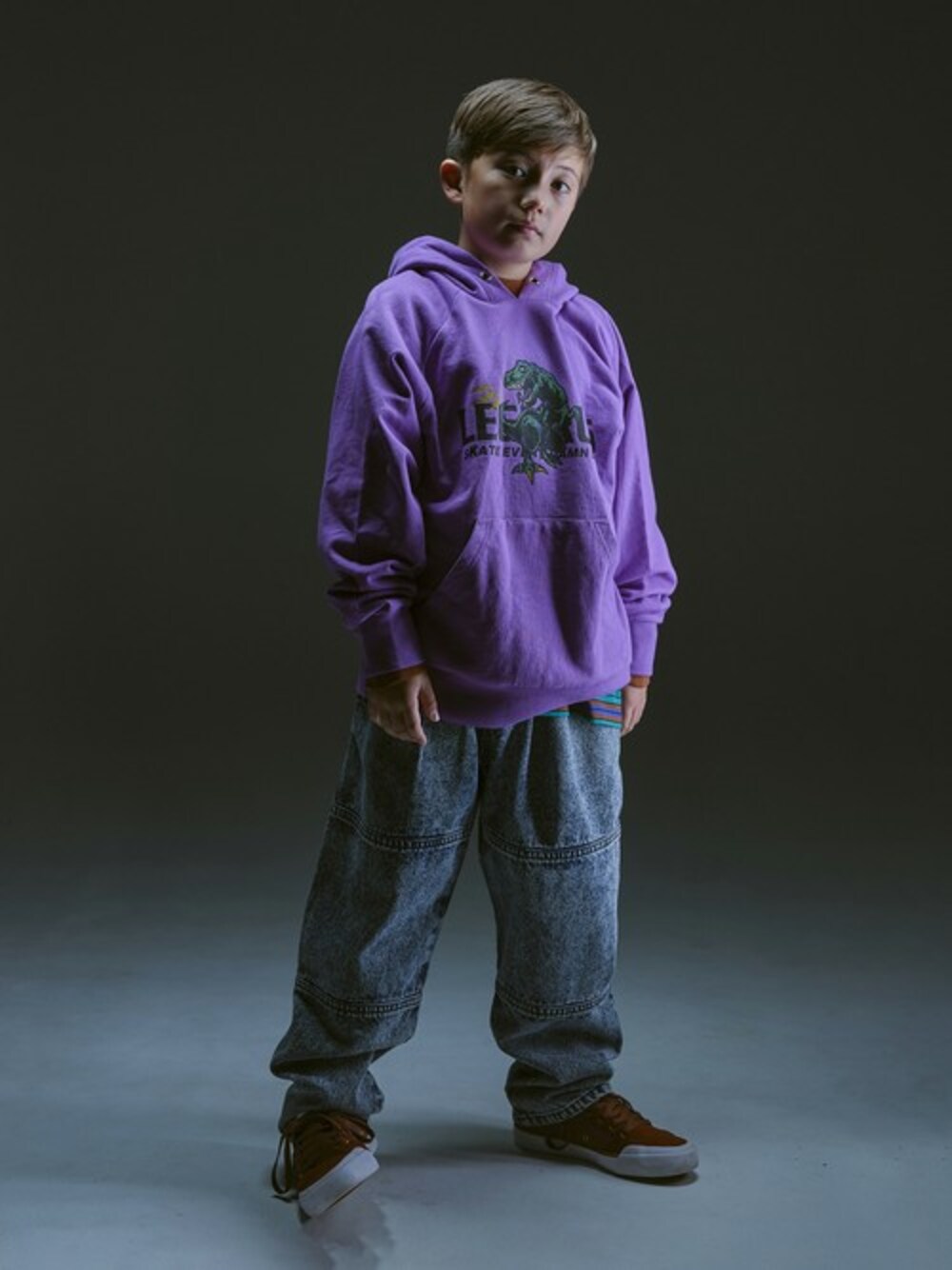 パープル系のパーカー、ブルー系のデニムパンツを着用したキッズの冬コーディネートの1枚目の写真