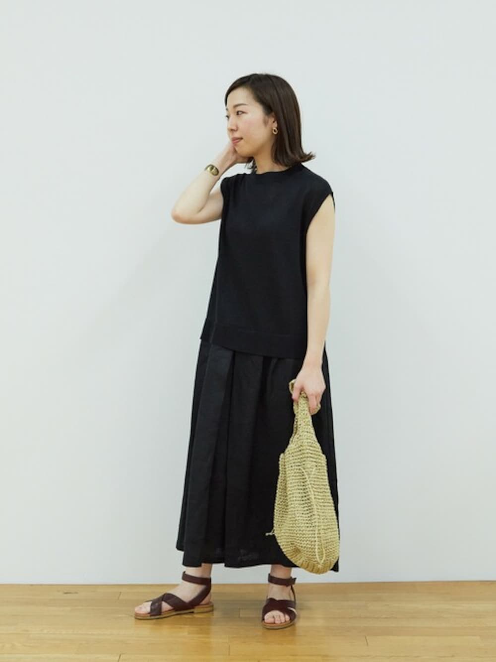ブラック系のワンピース、レッド系のサンダル、ベージュ系のショルダーバッグを着用したレディースの夏コーディネートの1枚目の写真