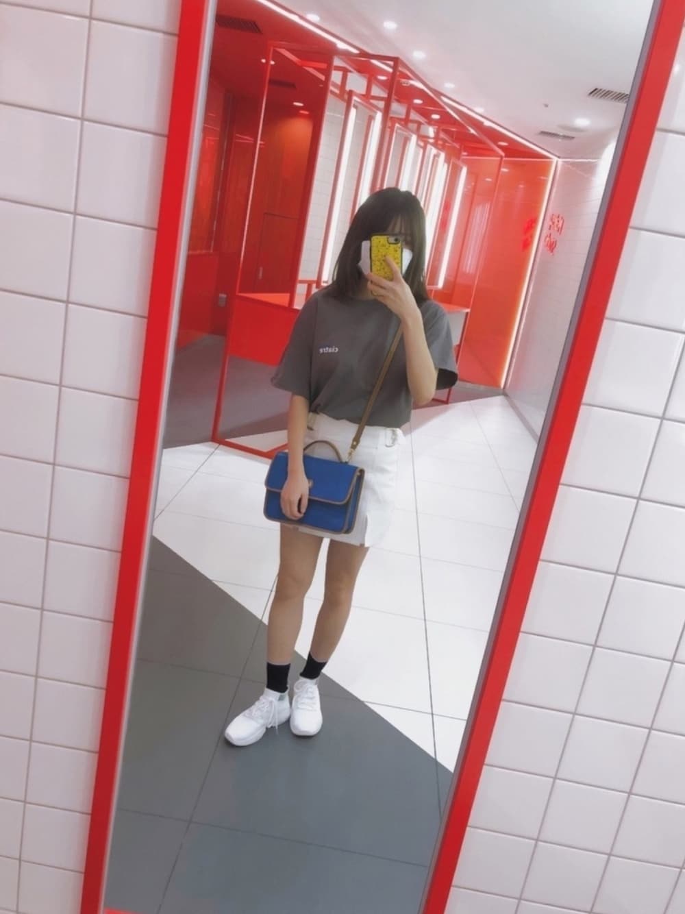 ブルー系のショルダーバッグ、ホワイト系のスニーカー、グレー系のTシャツ/カットソーを着用したレディースの夏コーディネートの1枚目の写真