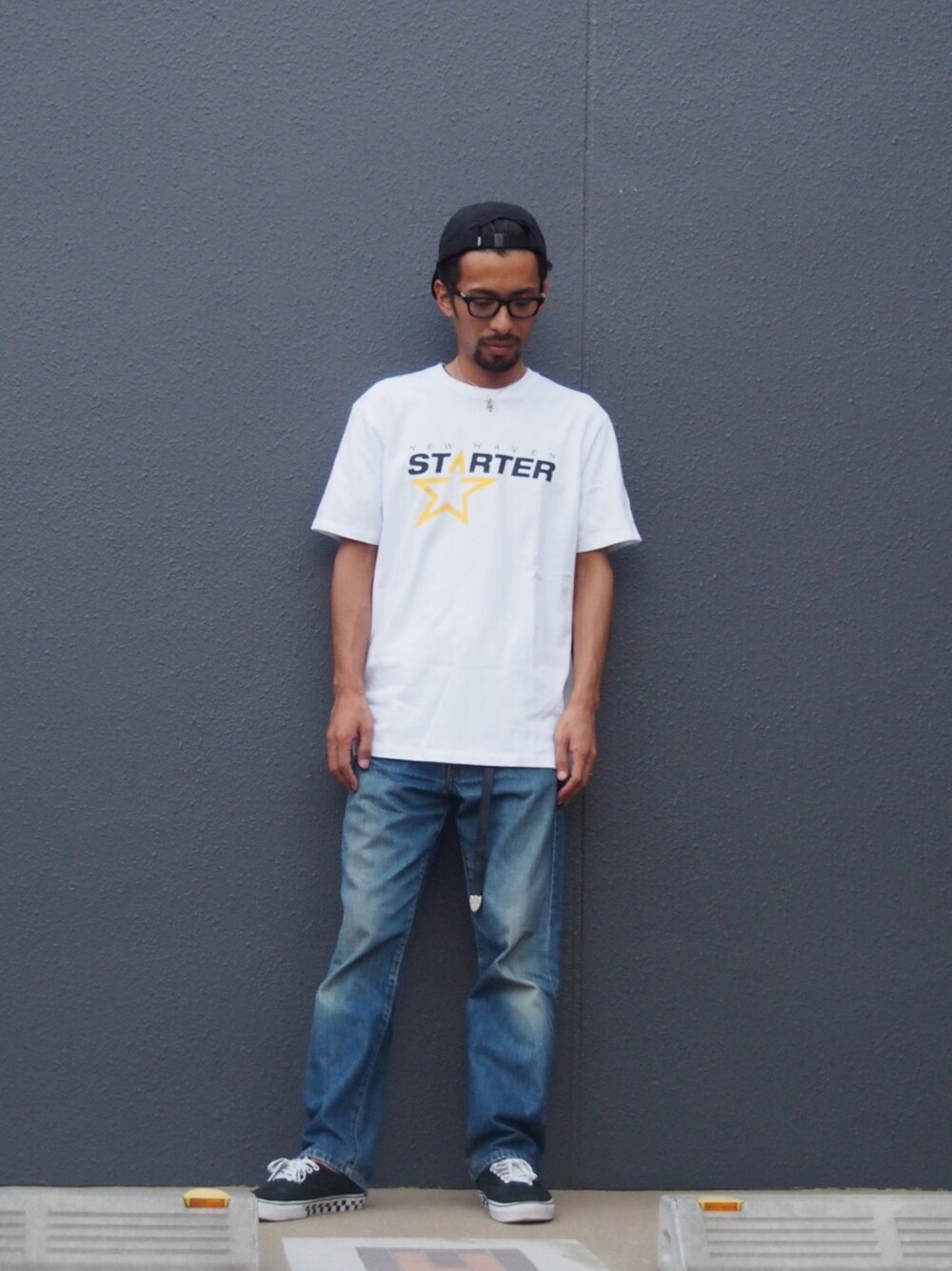 ホワイト系のTシャツ/カットソー、ブルー系のデニムパンツ、ブラック系のスニーカーを着用したメンズの夏コーディネートの1枚目の写真