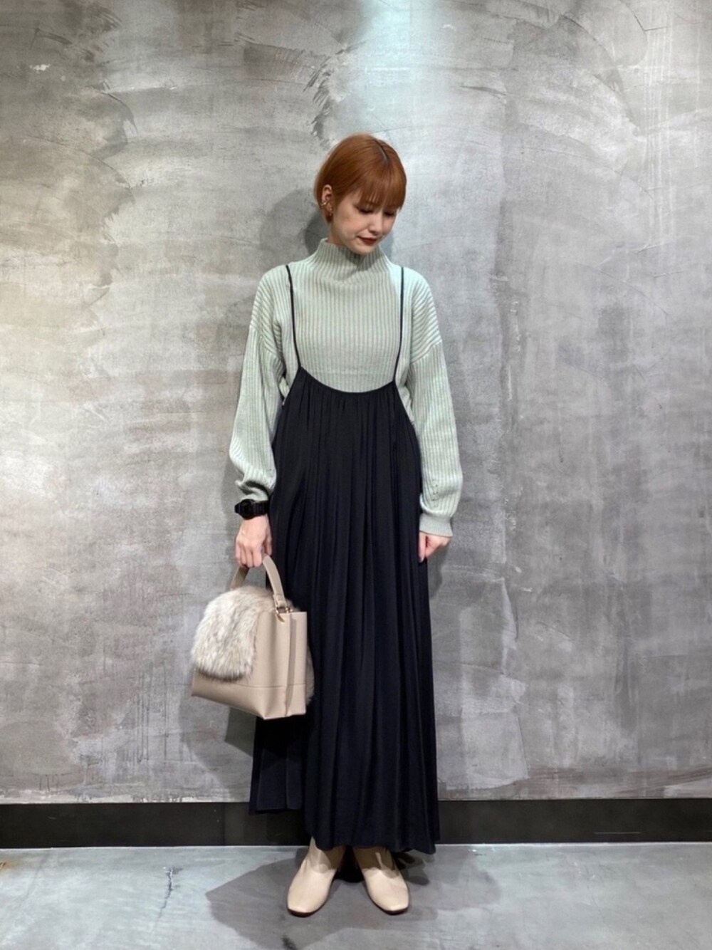 グリーン系のニット/セーター、ブラック系のワンピース、ベージュ系のハンドバッグを着用したレディースの冬コーディネートの1枚目の写真