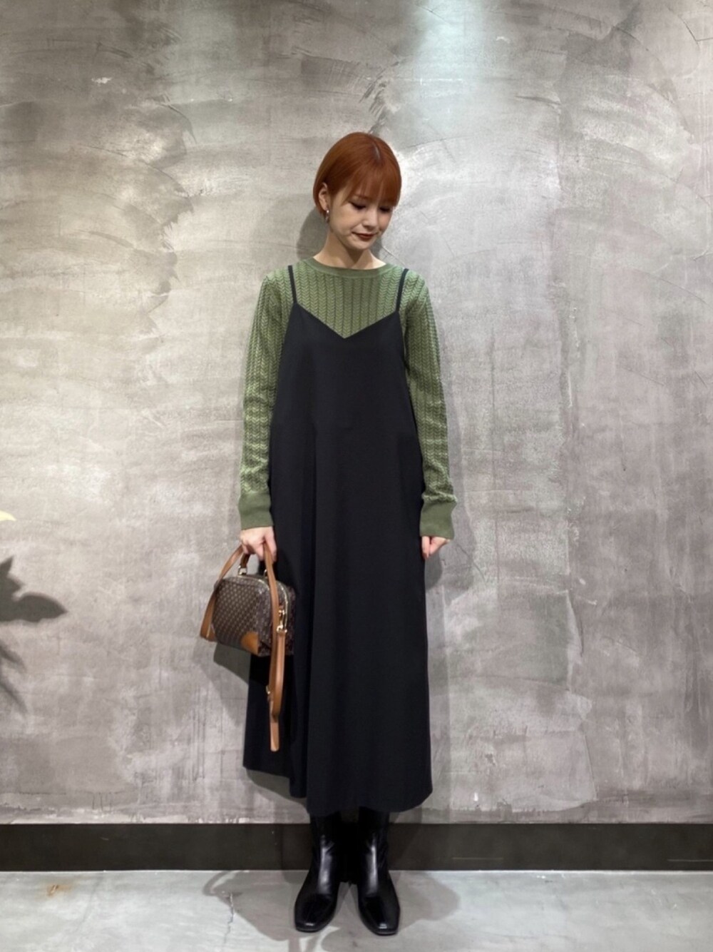 グリーン系のニット/セーター、ブラック系のワンピース、ブラック系のブーツを着用したレディースの冬コーディネートの1枚目の写真
