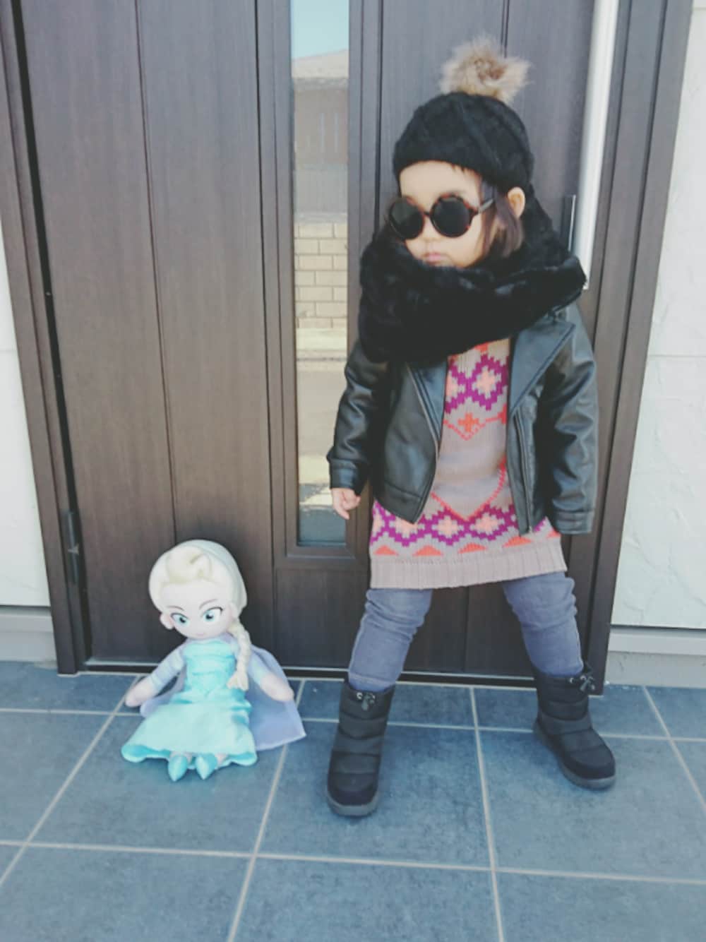 ベージュ系のワンピース、ホワイト系のTシャツ/カットソー、ブラック系のブーツを着用したキッズの冬コーディネートの1枚目の写真