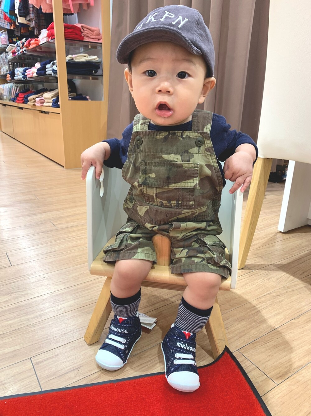 ブルー系のTシャツ/カットソー、グリーン系のロンパース、グレー系のキャップを着用したキッズの秋コーディネートの1枚目の写真