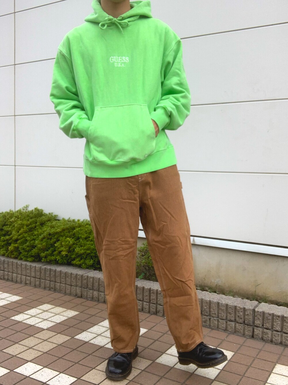 グリーン系のパーカー、ブラウン系のパンツ、ブラック系のブーツを着用したメンズの秋コーディネートの1枚目の写真