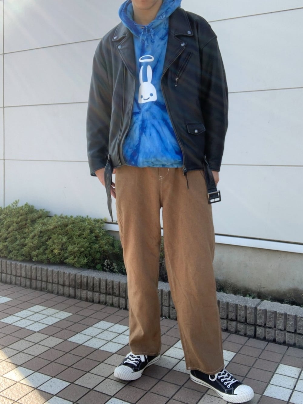 ブラック系のライダースジャケット、ブラウン系のパンツ、ブラック系のスニーカーを着用したメンズの秋コーディネートの1枚目の写真