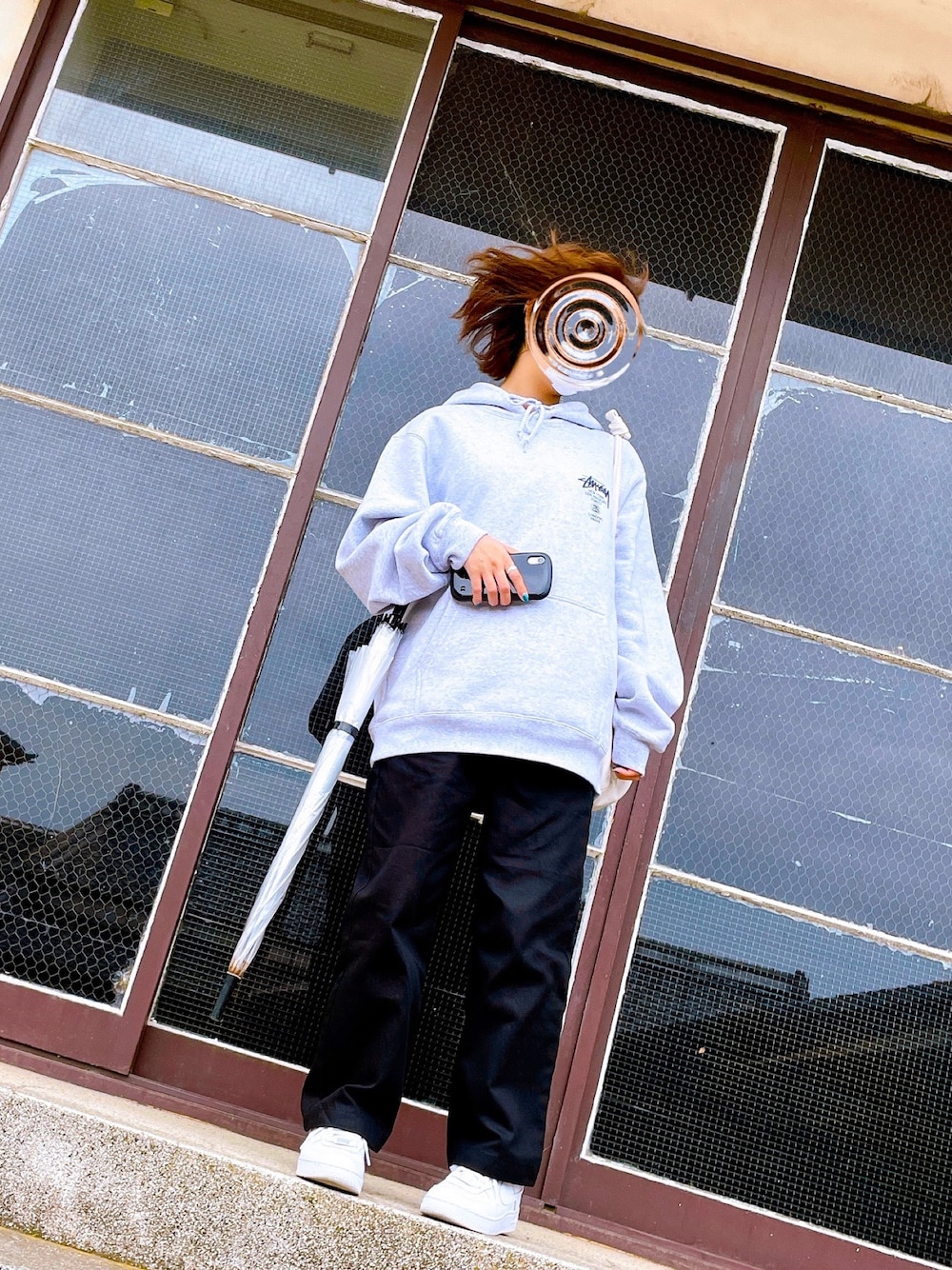グレー系のパーカー、ブラック系のチノパンツ、ホワイト系のスニーカーを着用したレディースの春コーディネートの1枚目の写真