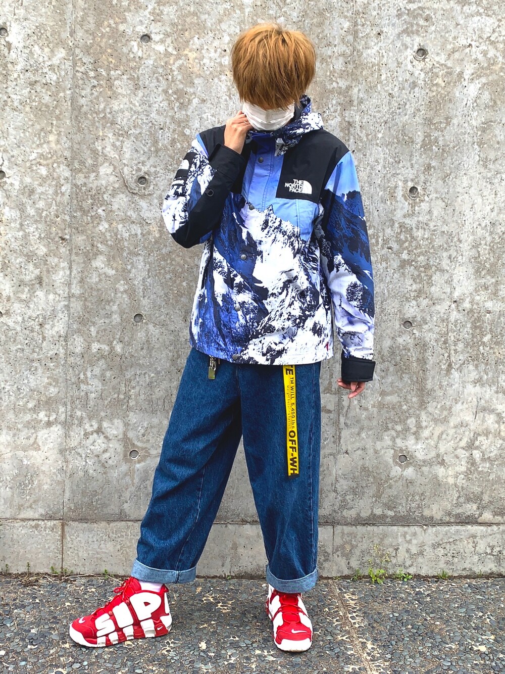 ブルー系のマウンテンパーカー、ブルー系のデニムパンツ、レッド系のスニーカーを着用したメンズの春コーディネートの1枚目の写真