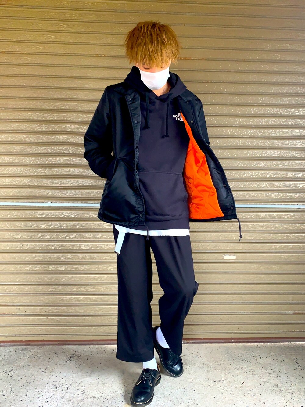 ブラック系のミリタリージャケット、ブラック系のパーカー、ブラック系のブーツを着用したメンズの春コーディネートの1枚目の写真