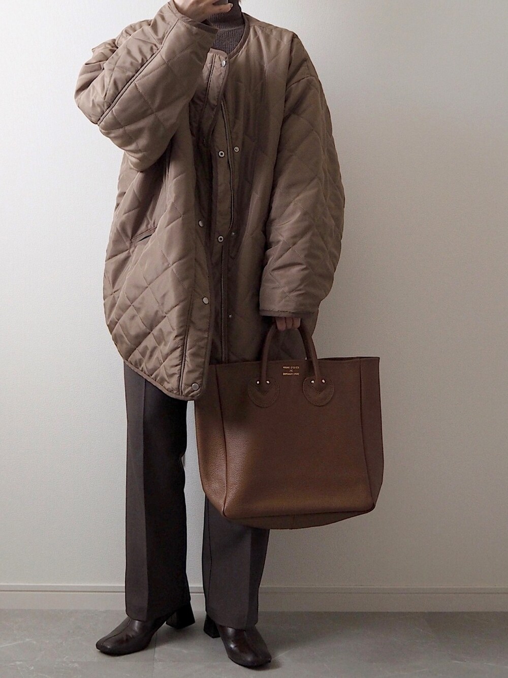 ブラウン系のダウンジャケット/コート、ブラウン系のトートバッグ、ブラウン系のスラックスを着用したレディースの冬コーディネートの1枚目の写真