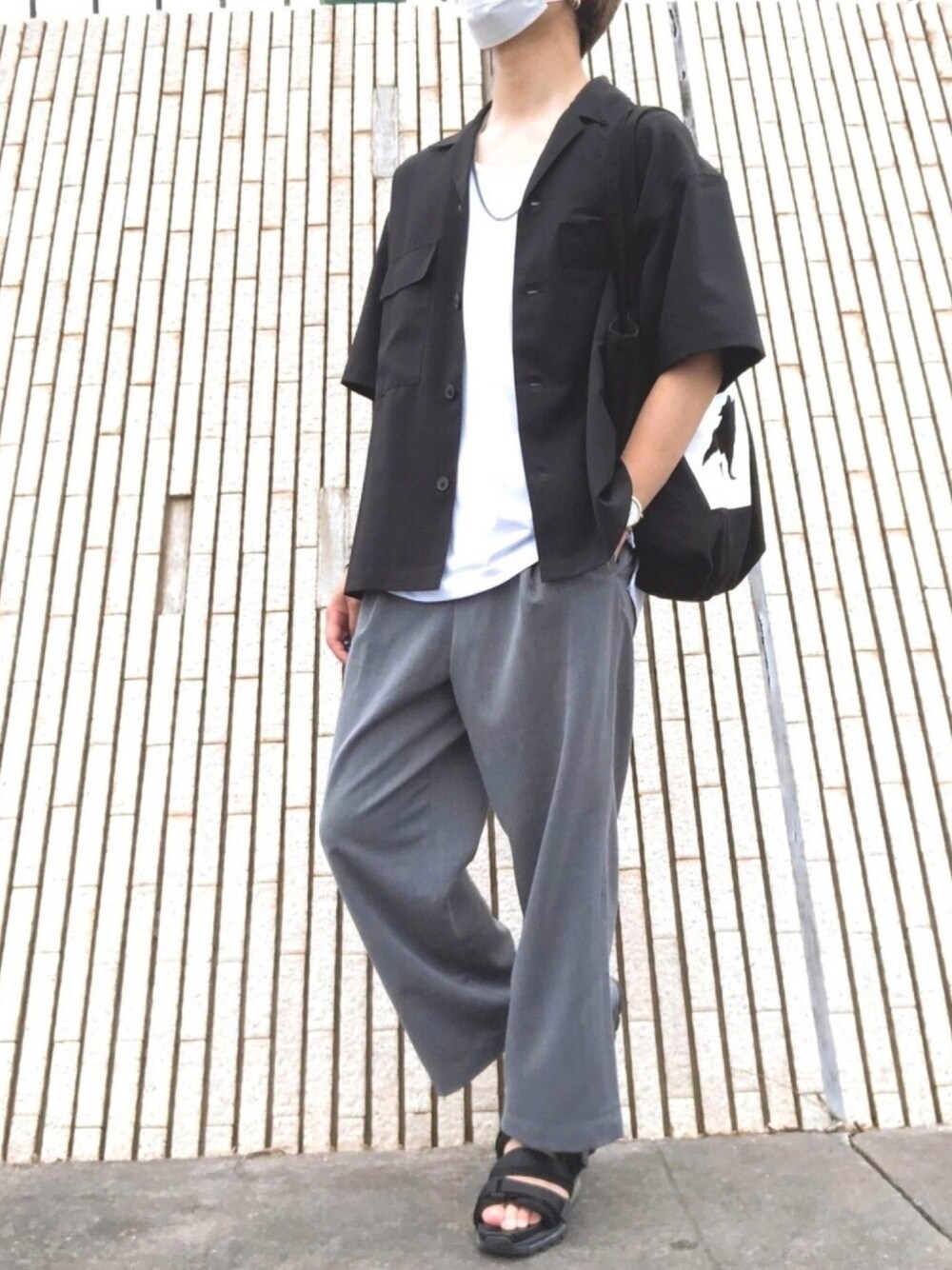 ブラック系のサンダル、グレー系のスラックス、ブラック系のトートバッグを着用したメンズの夏コーディネートの1枚目の写真