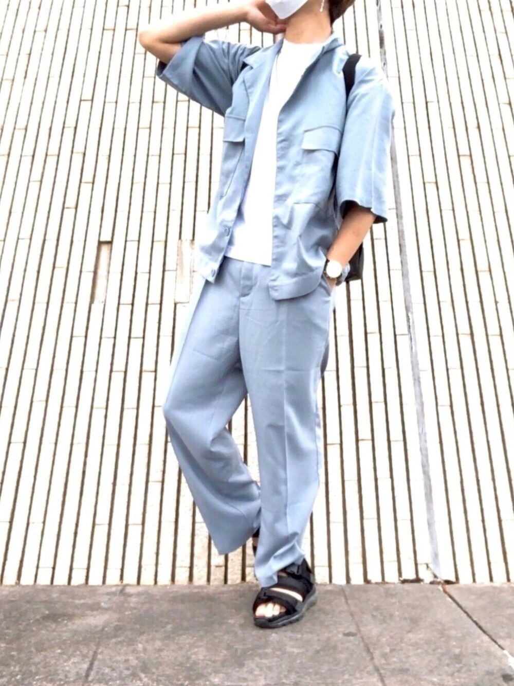 ブラック系のバックパック/リュック、ブラック系のサンダル、ブルー系のスラックスを着用したメンズの夏コーディネートの1枚目の写真