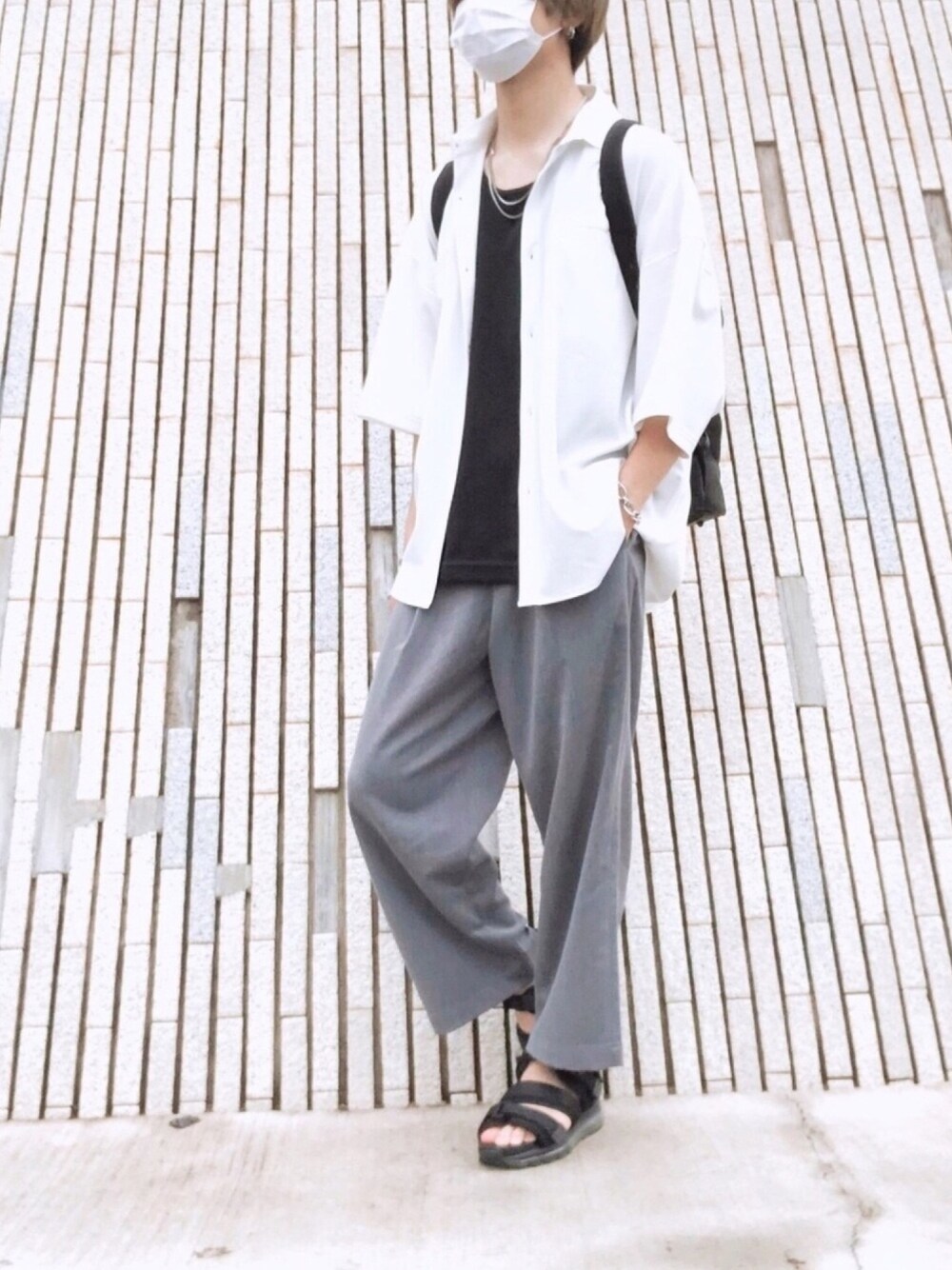 ブラック系のサンダル、グレー系のスラックス、ブラック系のバックパック/リュックを着用したメンズの夏コーディネートの1枚目の写真