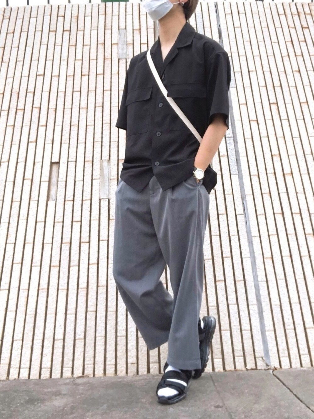 ブラック系のサンダル、ホワイト系のショルダーバッグ、グレー系のスラックスを着用したメンズの夏コーディネートの1枚目の写真