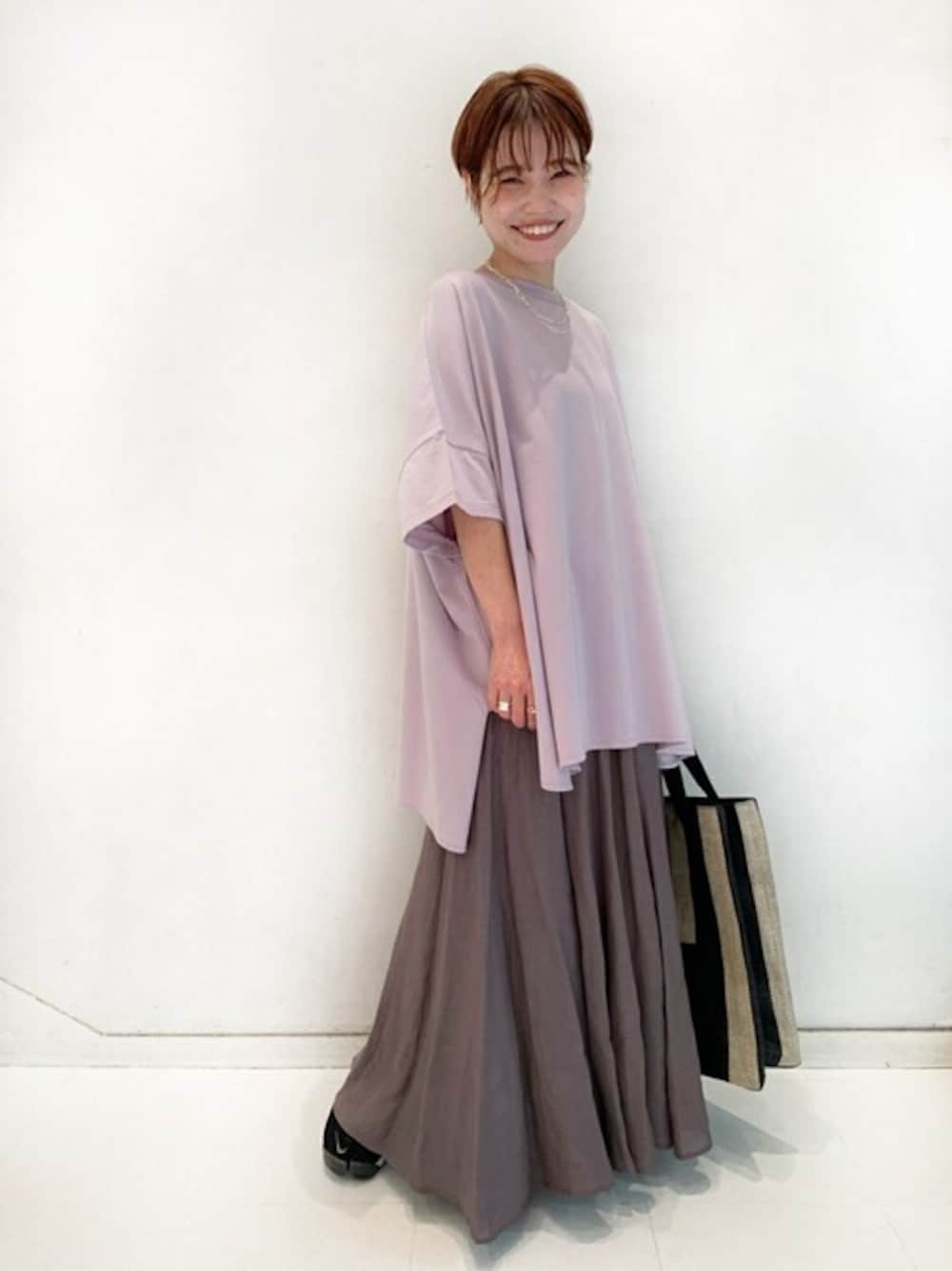 パープル系のTシャツ/カットソー、グレー系のスカート、ベージュ系のトートバッグを着用したレディースの春コーディネートの1枚目の写真