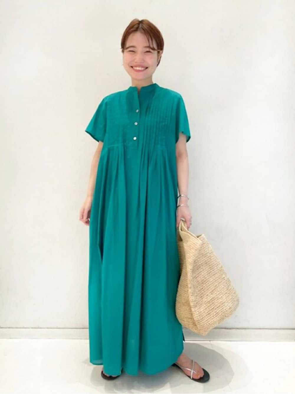 グリーン系のワンピース、ホワイト系のかごバッグ、シルバー系のサンダルを着用したレディースの春コーディネートの1枚目の写真