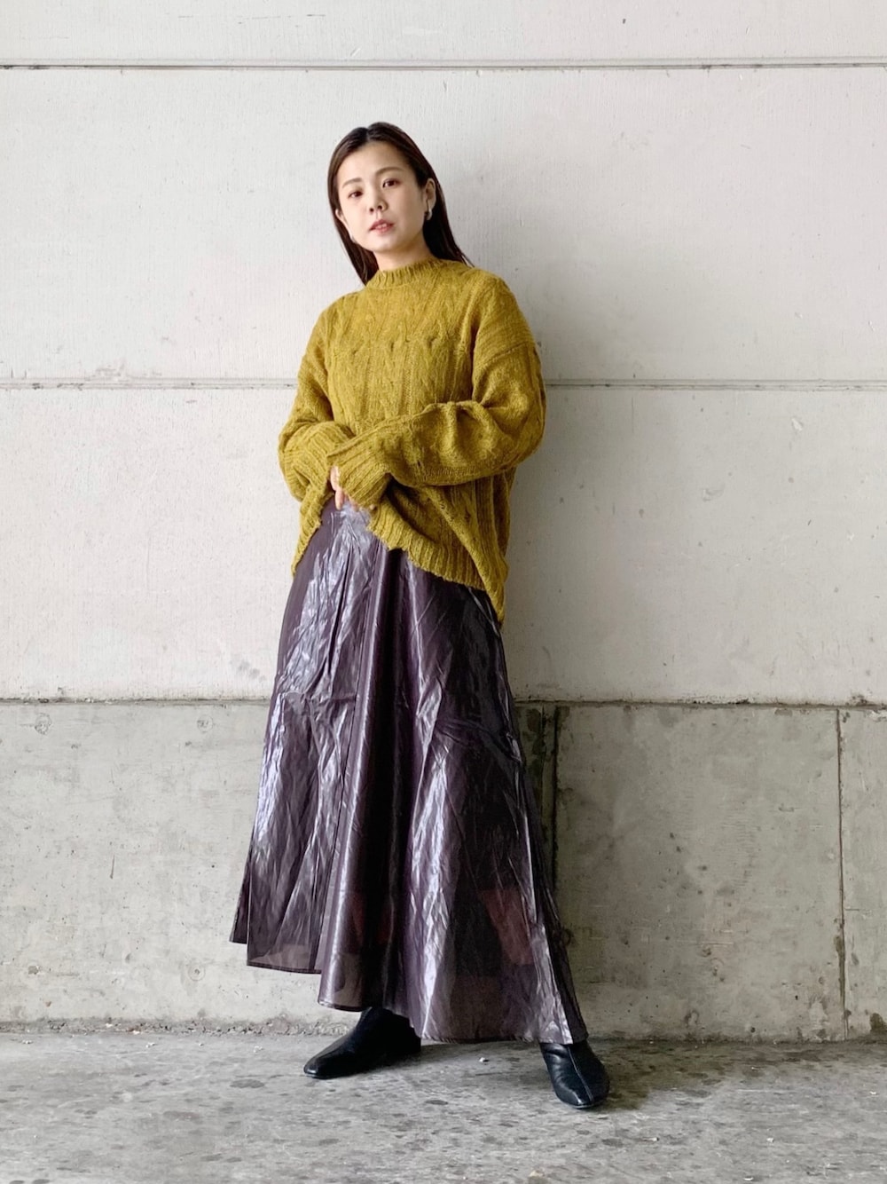 イエロー系のニット/セーター、グレー系のスカート、ブラック系のブーツを着用したレディースの秋コーディネートの1枚目の写真