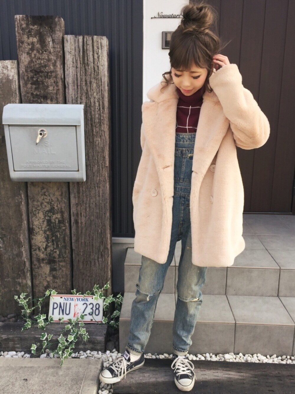 ベージュ系のピーコート、ブルー系のオールインワン・サロペット、ブラック系のスニーカーを着用したレディースの冬コーディネートの1枚目の写真