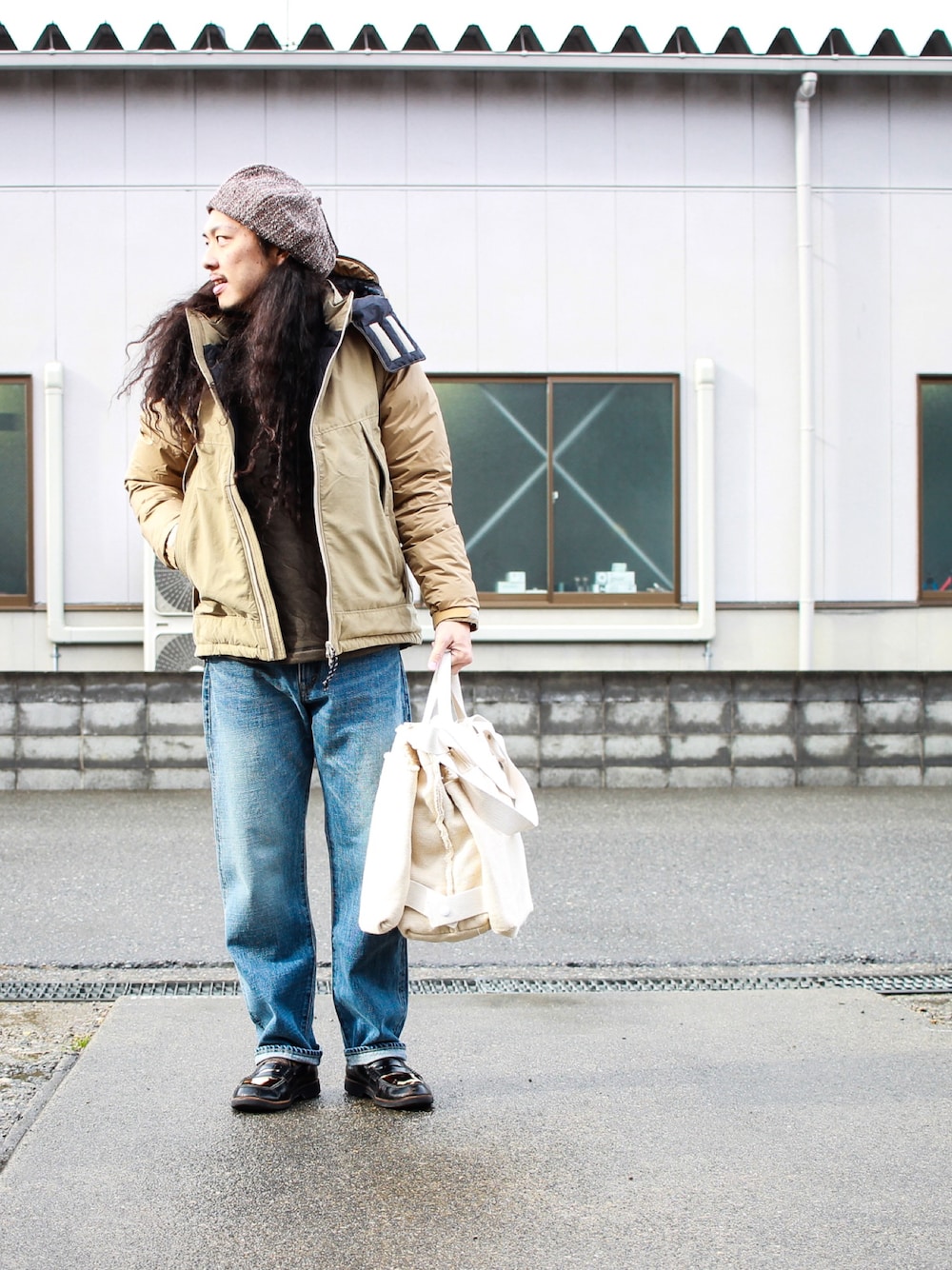 ベージュ系のダウンジャケット/コート、ブルー系のデニムパンツを着用したメンズの冬コーディネートの1枚目の写真