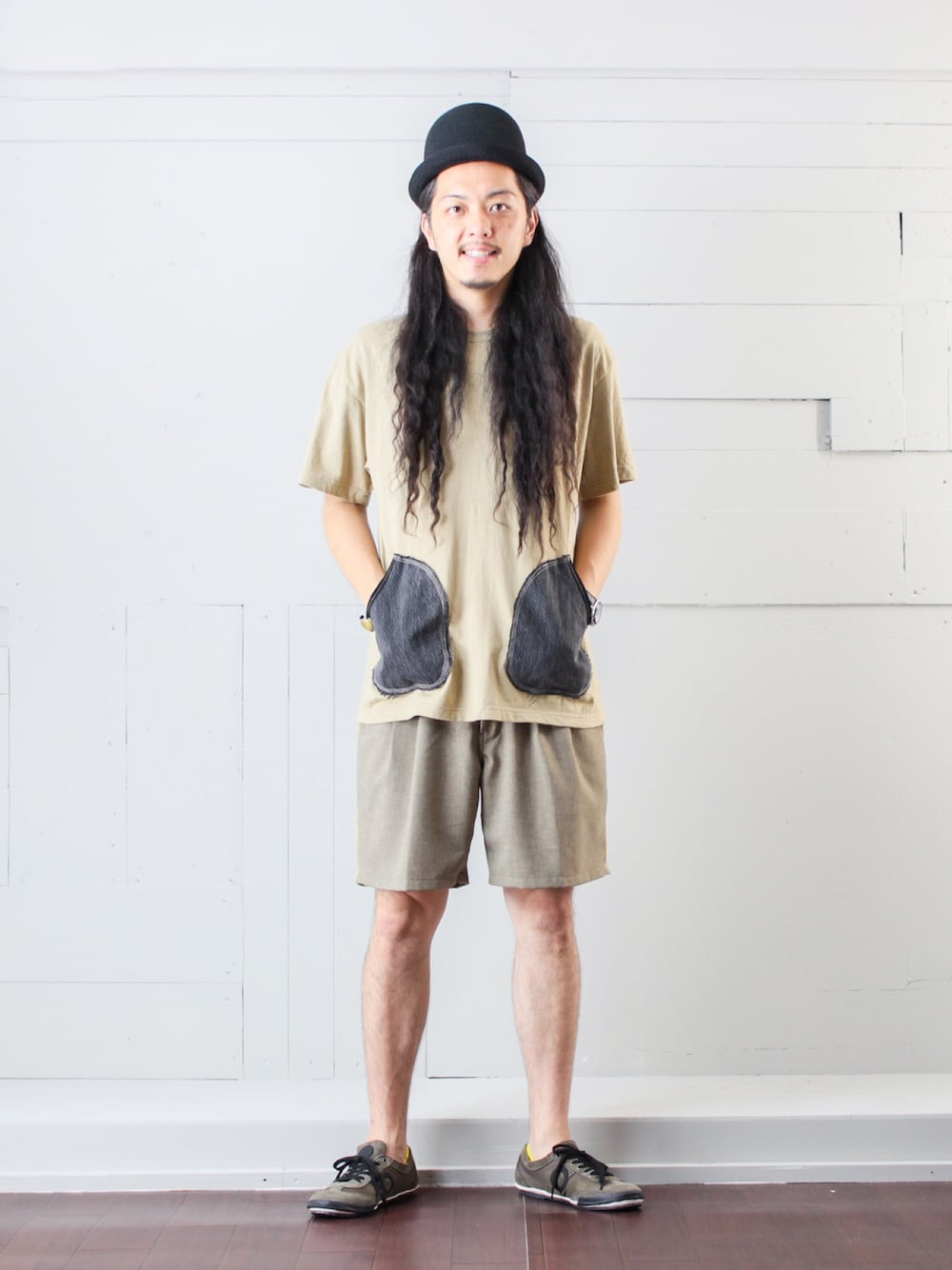 ベージュ系のTシャツ/カットソー、ベージュ系のスラックス、グレー系のスニーカーを着用したメンズの夏コーディネートの1枚目の写真