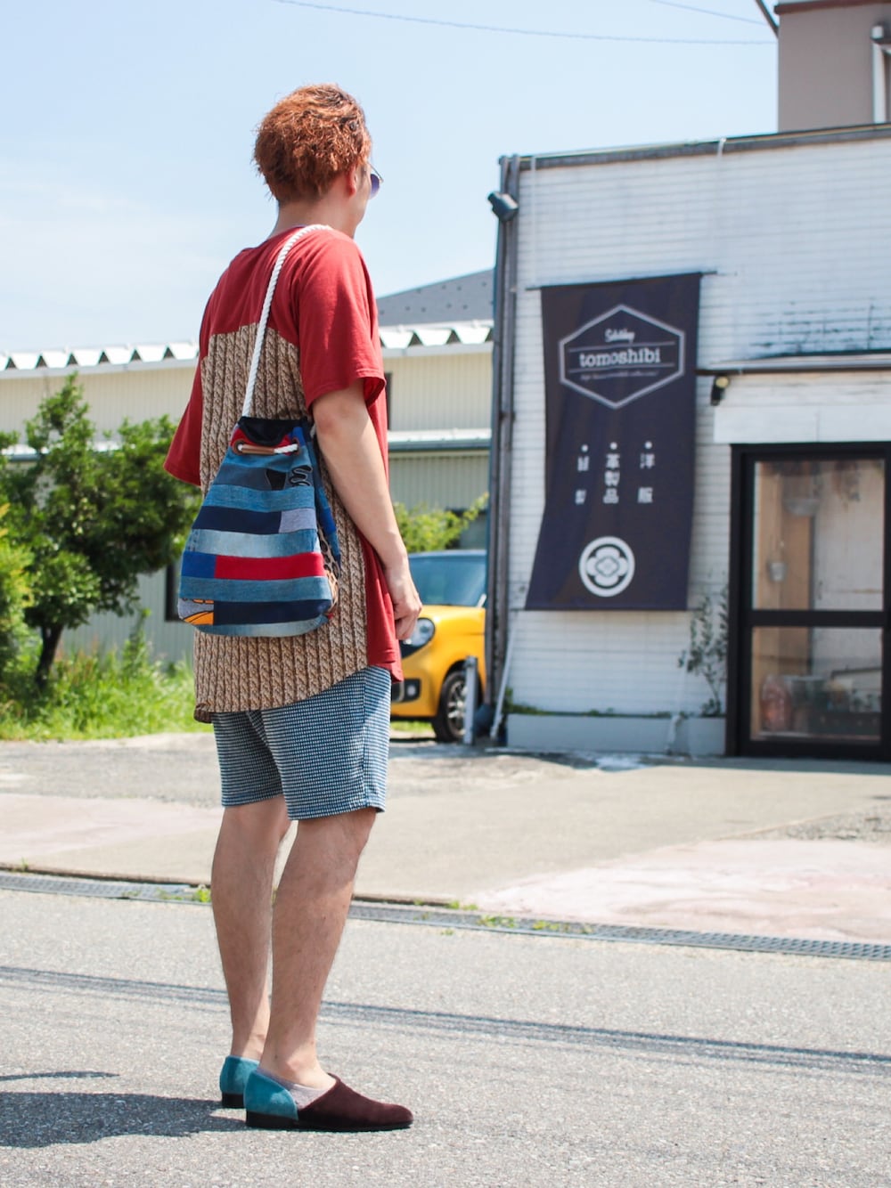 レッド系のTシャツ/カットソー、ブルー系のショルダーバッグ、ブルー系のパンツを着用したメンズの夏コーディネートの1枚目の写真