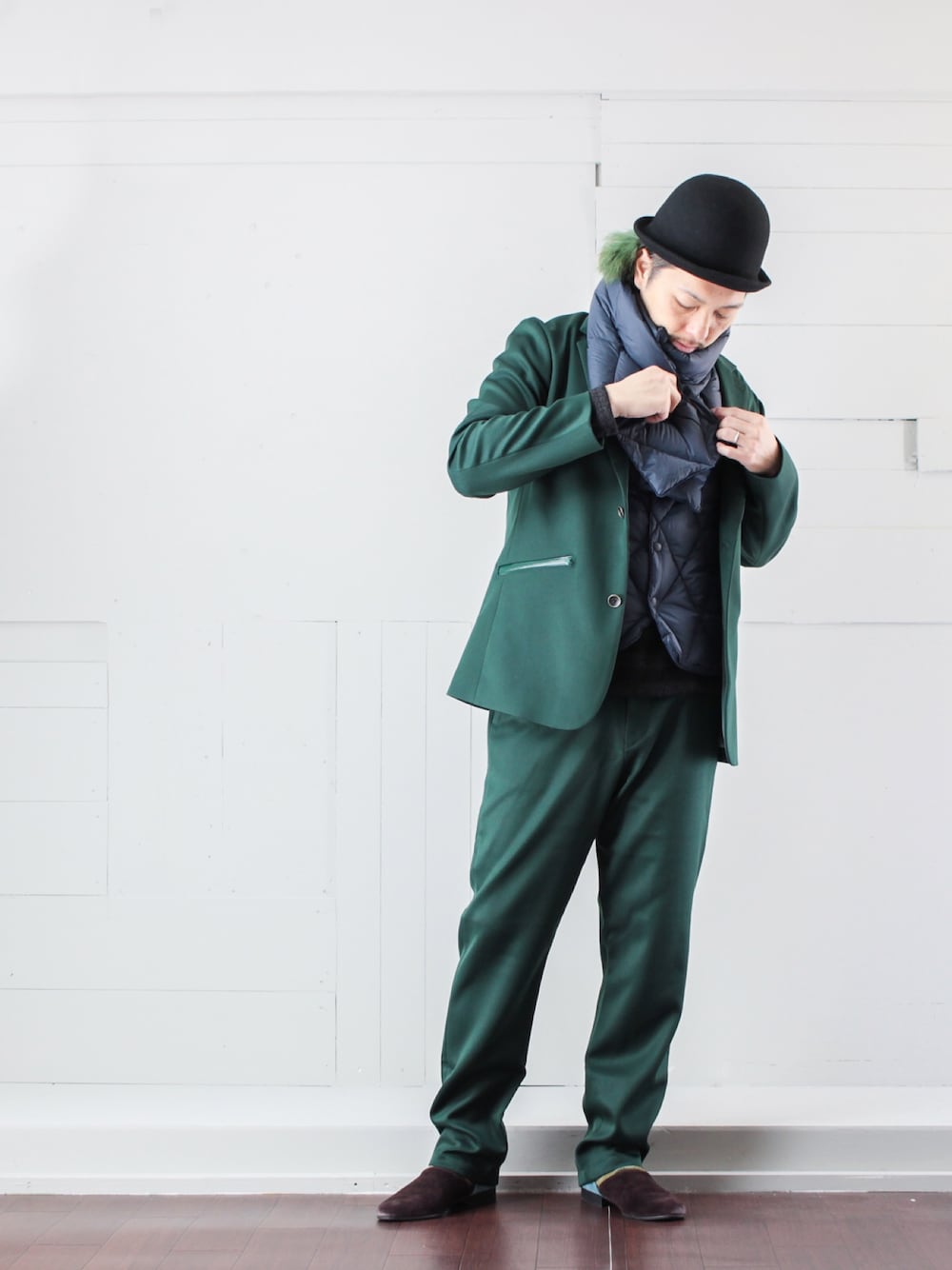 グリーン系のテーラードジャケット、グリーン系のスラックス、ブルー系のダウンベストを着用したメンズの秋コーディネートの1枚目の写真