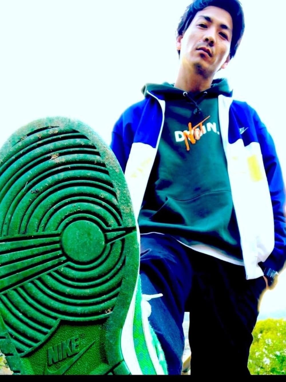 ブラック系のカーゴパンツ、ホワイト系のナイロンジャケット、グリーン系のスニーカーを着用したメンズの秋コーディネートの1枚目の写真