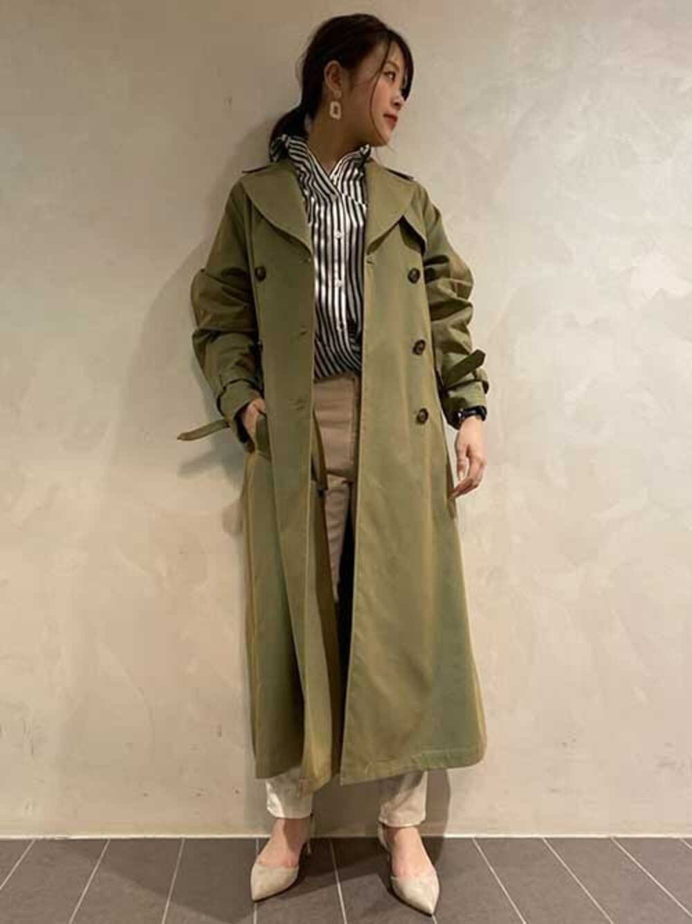 グリーン系のトレンチコート、ブラック系のシャツ/ブラウス、グレー系のパンプスを着用したレディースの春コーディネートの1枚目の写真