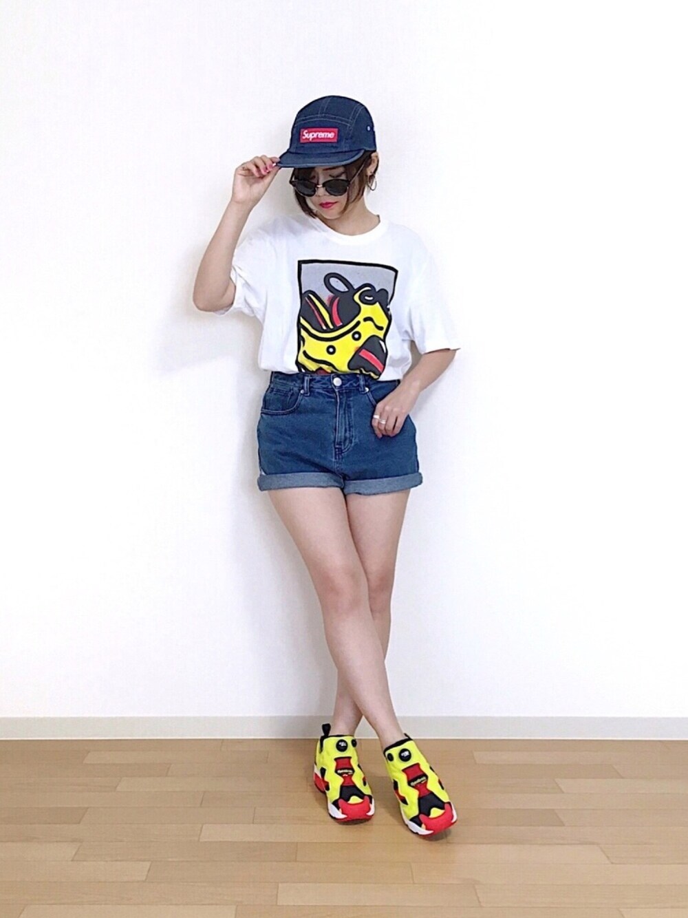 ブルー系のデニムパンツ、イエロー系のスニーカー、ブルー系のキャップを着用したレディースの春コーディネートの1枚目の写真