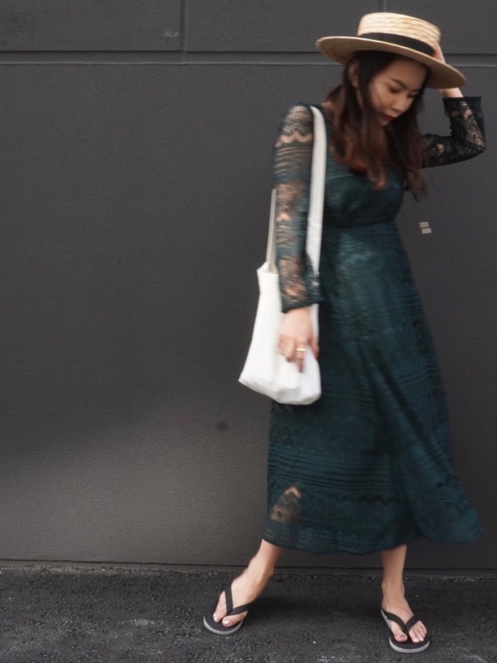 ブラック系のビーチサンダル、グリーン系のワンピース、ベージュ系のハットを着用したレディースの秋コーディネートの1枚目の写真