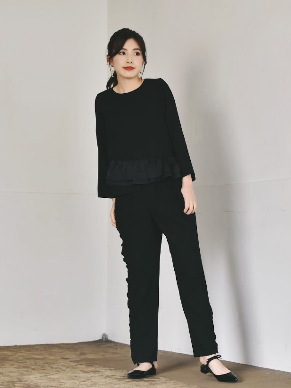 ブラック系のスラックス、ブラック系のシャツ/ブラウス、ゴールド系のピアス(両耳用)を着用したレディースの冬コーディネートの1枚目の写真