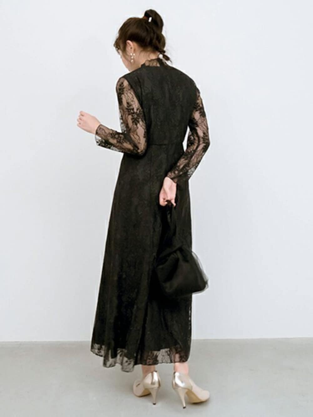 ブラック系のドレス、ブラック系のハンドバッグを着用したレディースの冬コーディネートの1枚目の写真