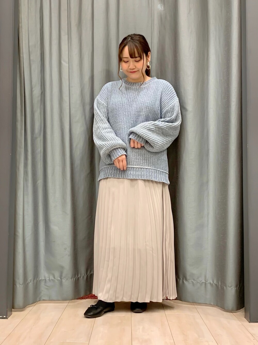 ブルー系のニット/セーター、ホワイト系のスカート、ブラック系のパンプスを着用したレディースの冬コーディネートの1枚目の写真