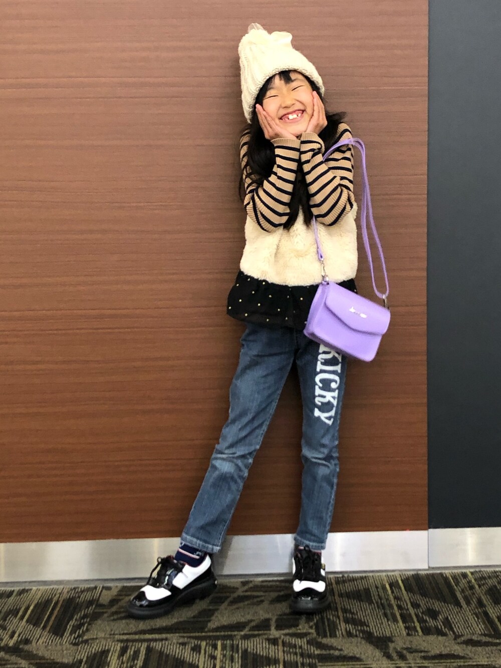 ベージュ系のキャミソール、ブルー系のデニムパンツ、ホワイト系のスニーカーを着用したキッズの冬コーディネートの1枚目の写真