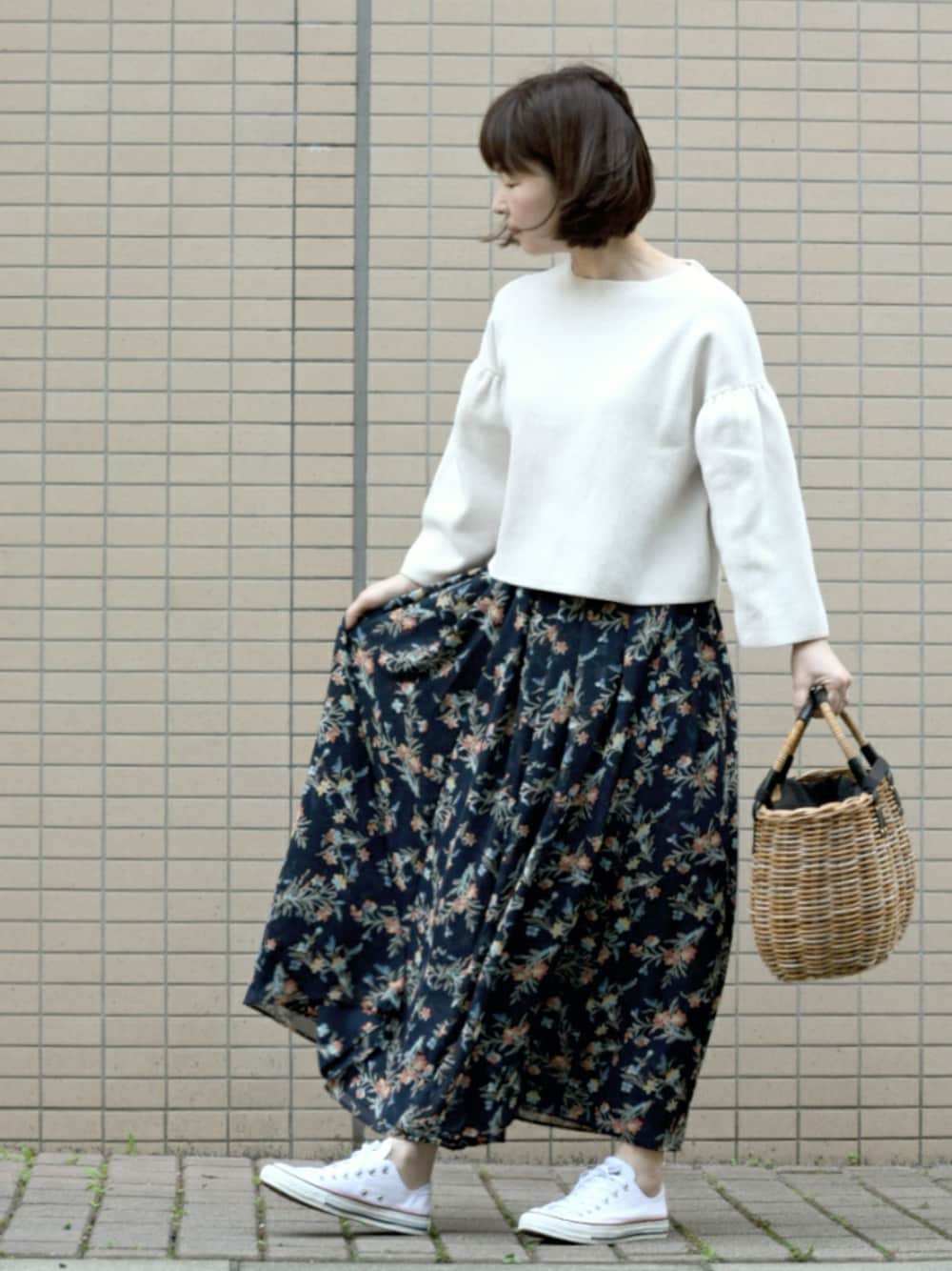 ブルー系のスカート、ベージュ系のトートバッグ、ホワイト系のスニーカーを着用したレディースの春コーディネートの1枚目の写真