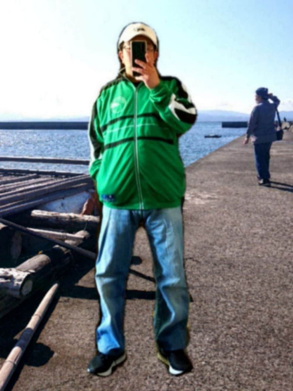 グリーン系のジャージ、ブルー系のデニムパンツ、ブラック系のスニーカーを着用したメンズの春コーディネートの1枚目の写真