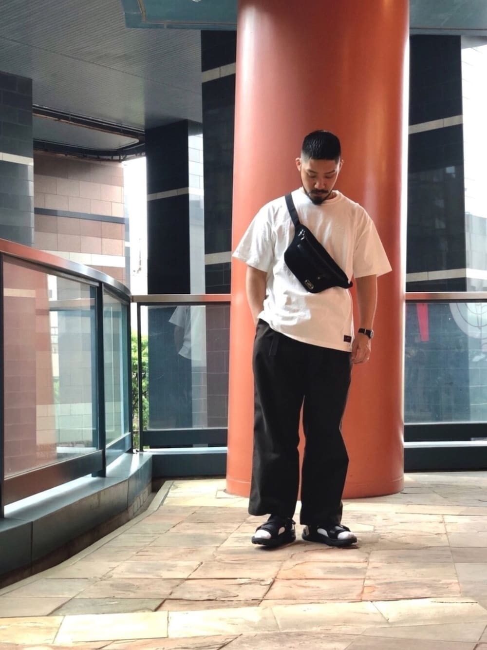 ホワイト系のTシャツ/カットソー、ブラック系のボディバッグ/ウエストポーチ、ブラウン系のスラックスを着用したメンズの春コーディネートの1枚目の写真