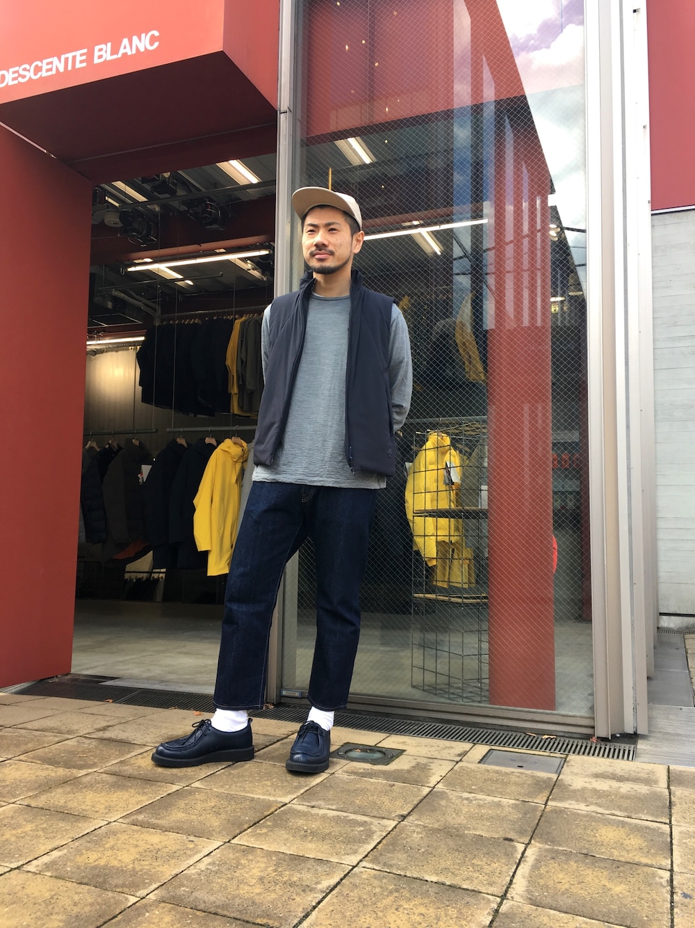 グレー系のニット/セーター、ブラック系のベスト、ブルー系のシューズを着用したメンズの冬コーディネートの1枚目の写真