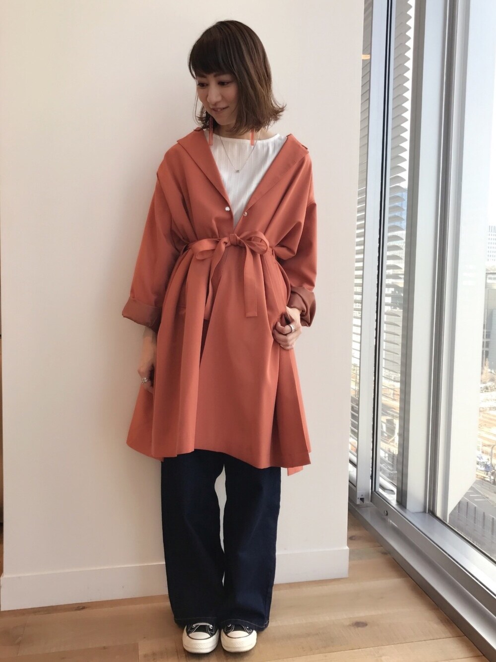 グレー系のチェスターコート、ホワイト系のシャツ/ブラウス、ブルー系のデニムパンツを着用したレディースの冬コーディネートの1枚目の写真