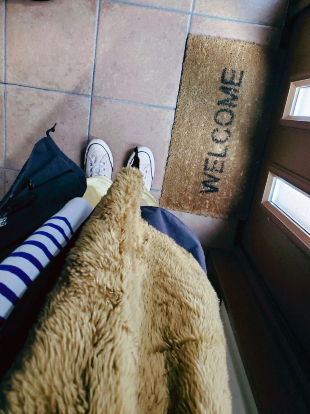 ブラウン系のベスト、ブルー系のTシャツ/カットソー、ブラック系のモッズコートを着用したレディースの春コーディネートの1枚目の写真